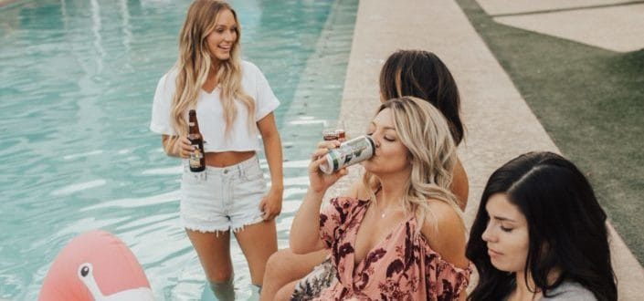 Ladies drinking beer while chilling beside the pool