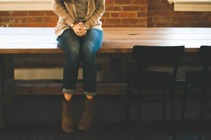 Girl sitting on a long wooden table.