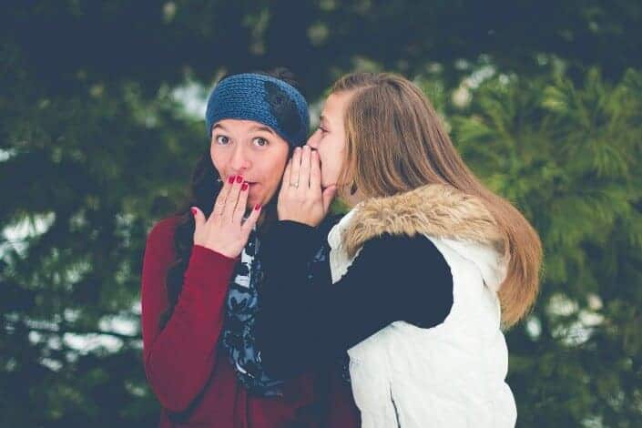 One girl whispering to another girl