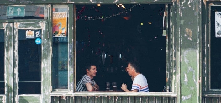 Two men talking to each other beside the window of an old cafe