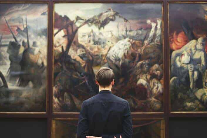A man looking at a huge painting on the wall