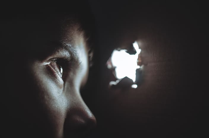 Woman looking outside through a hole