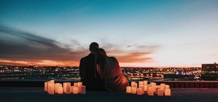 couple sitting on the field facing the city