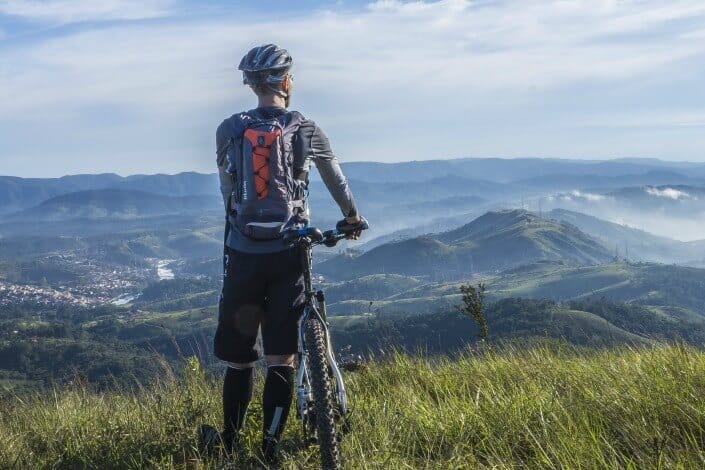 biker holding his bike on top of mountain