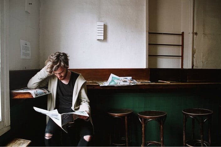 man reading newspaper near the window