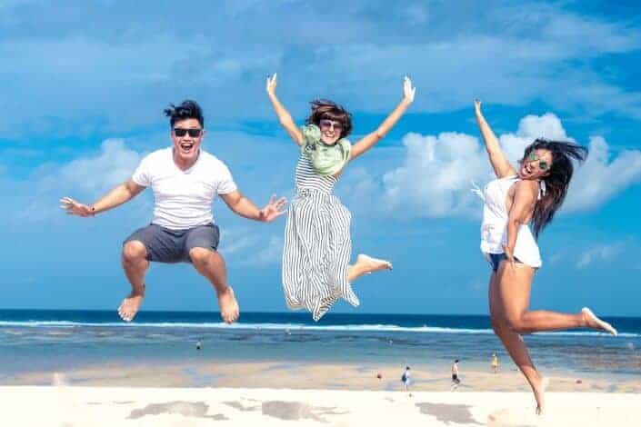 Friends taking a jumpshot on the beach.