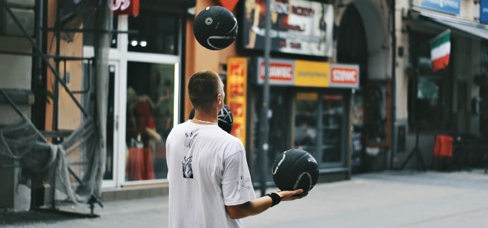 man juggling basketballs near storefront
