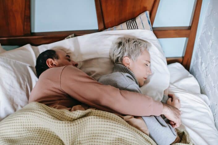 sleeping-ethnic-man-hugging-wife-on-bed-