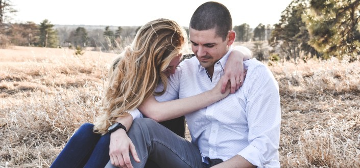 Couple sitting on a field, having intimate moment.