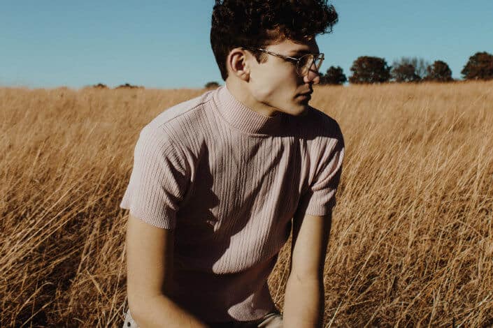 Guy with a serious face, sitting on a field.