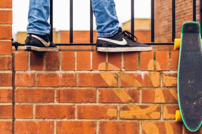 A person and a skateboard on a brickwall.