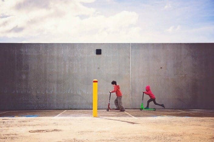 two kids playing with their scooters