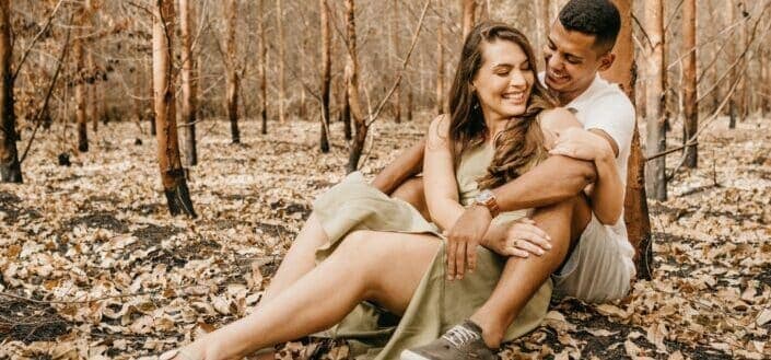 Couple sitting on dry leaves in the forest