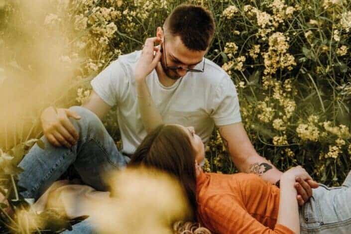 Couple sitting on bushes field with flowers