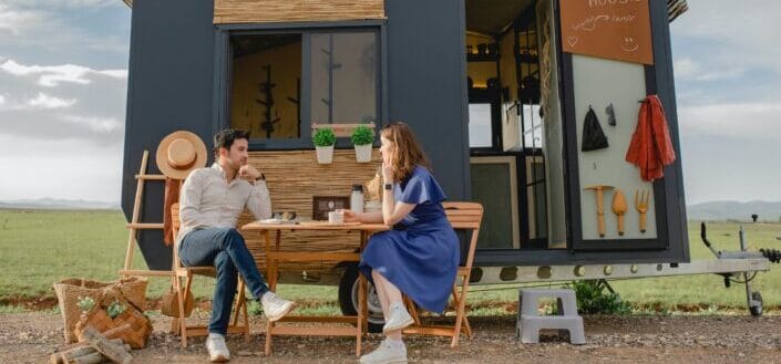 young-couple-sitting-at-table-in-front-of-mobile-home-pexels