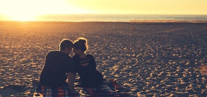 Couple enjoying sweet moments along the beach while sun is coming down