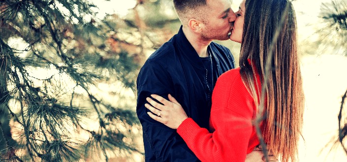 Sweet couple kissing underneath the pine tree