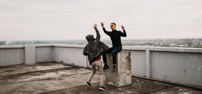Two men jumping high five at the rooftop