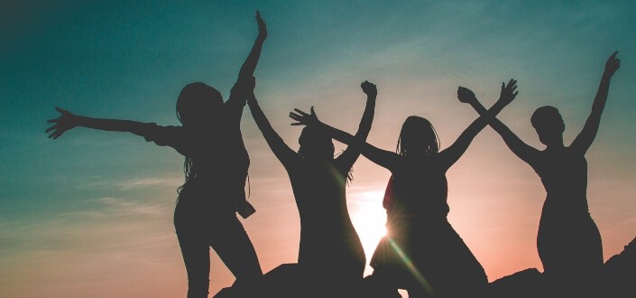 Silhouette of four girls with arms up