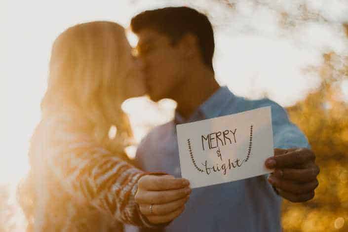 Couple kissing while holding Merry & bright card