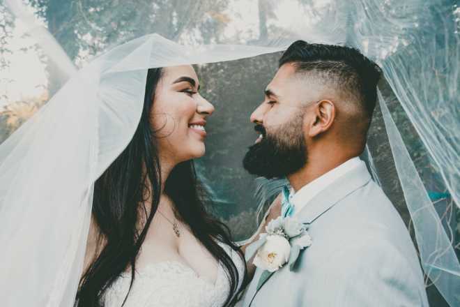 Newlywed couple smiling at each other under bride's veil - Newlywed Game Questions