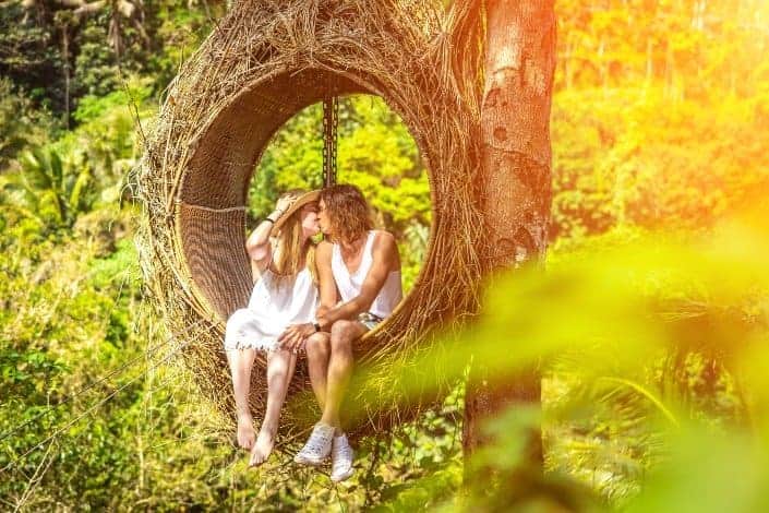 Couple kissing in a suspended bird nest swing