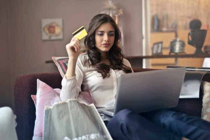 Girl shopping on her laptop and holding a yellow card