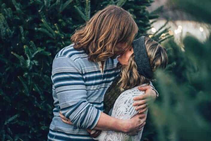 Couple kissing with trees around them