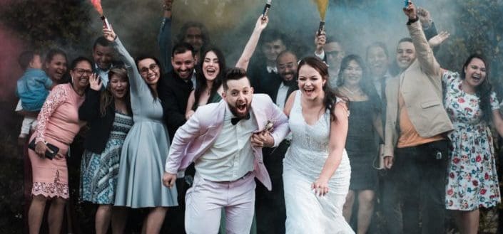 Newlywed couple candidly posing with their guests behind them