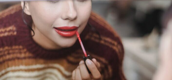 woman-applying-red-lipstick-while-preparing-for-event-