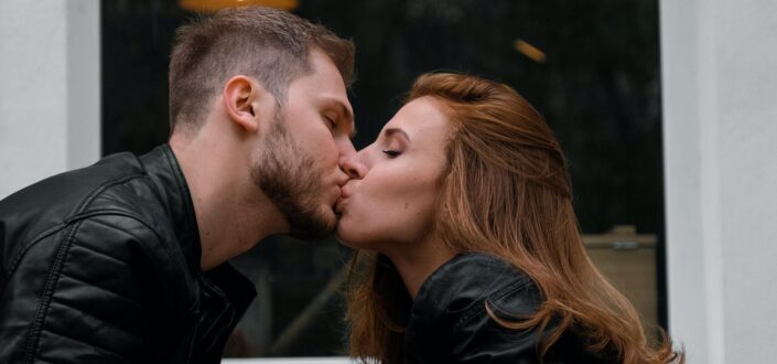 kissing couple wearing black jackets 