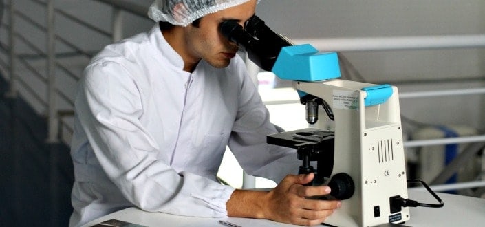 A man looking at his experiment on a microscope