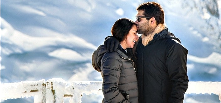 Man kissing her woman in forehead while enjoying the snowy weather