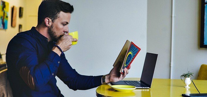 Man reading book while sipping his coffee