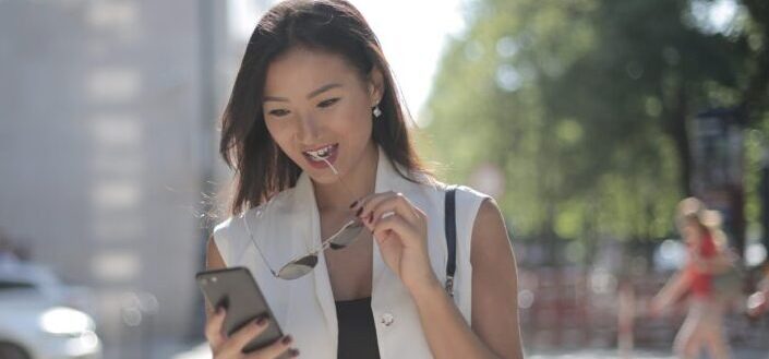 woman-in-white-sleeveless-dress-holding-black-smartphone-