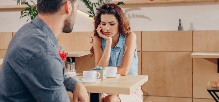 Couple looking gloomy while having a talk over a cup of coffee