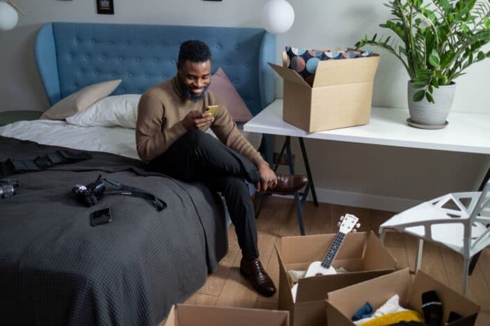 a-man-using-his-smartphone-while-sitting-on-a-bed-