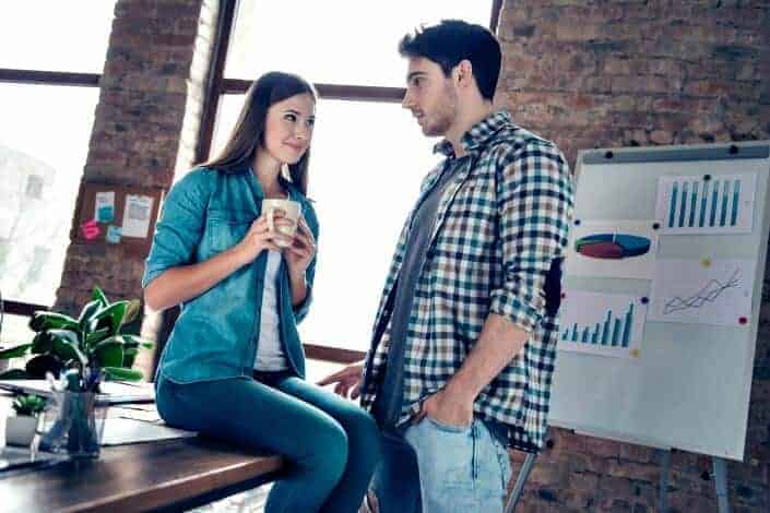 coworkers talking while one is holding coffee