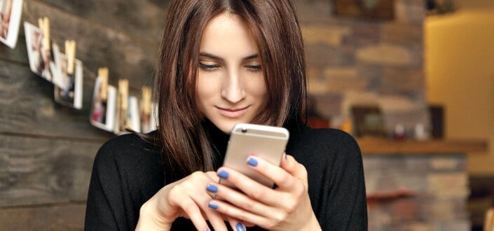woman in black shirt smiling at her phone