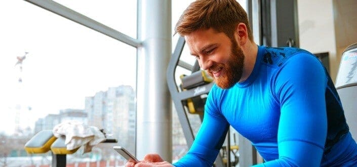 man in blue shirt smiling at his phone