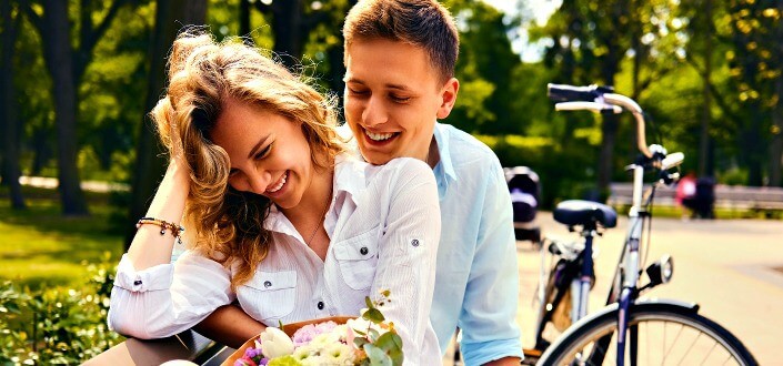 a couple laughing and being sweet to each other with a bike in the background