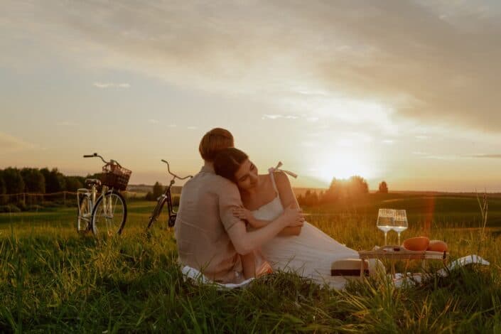 a-couple-having-a-picnic-on-a-grass-field-while-hugging-each-other-