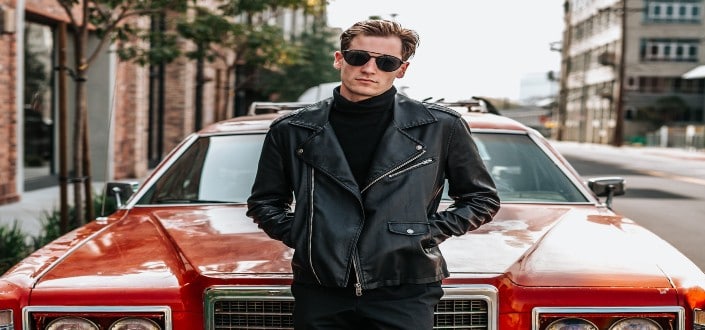 A man in style posing in front of his red vintage car