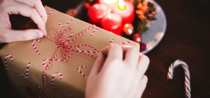 person tying the ribbon of the gift box