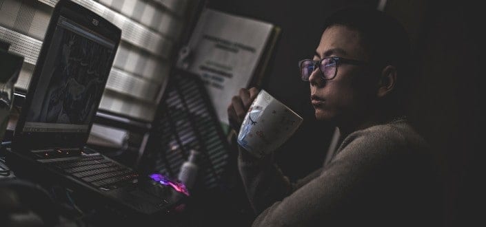 man holding mug in front of laptop
