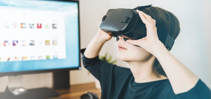 woman using black VR headset beside computer