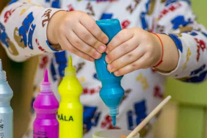 Little boy putting blue paint in cup