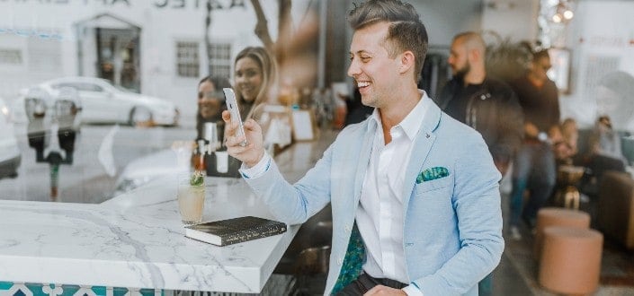 A smiling man in a formal attire looking at his phone