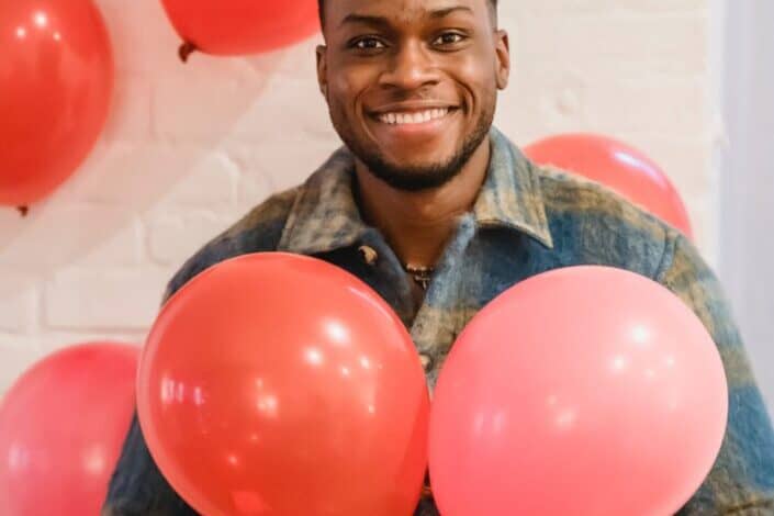 cheerful-black-man-with-colorful-party-balloons-