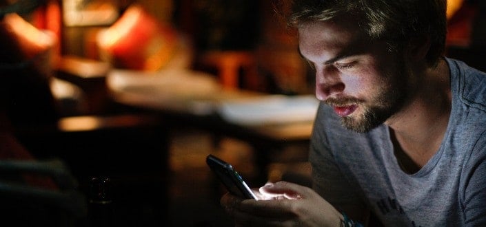 A serious looking man sending message on his phone